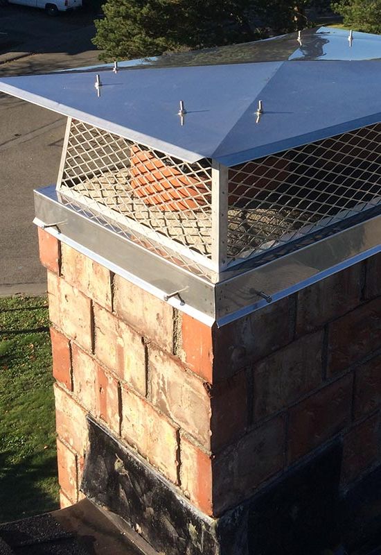 A stainless steel chimney cap installed on a brick chimney A stainless steel chimney cap installed on a brick chimney