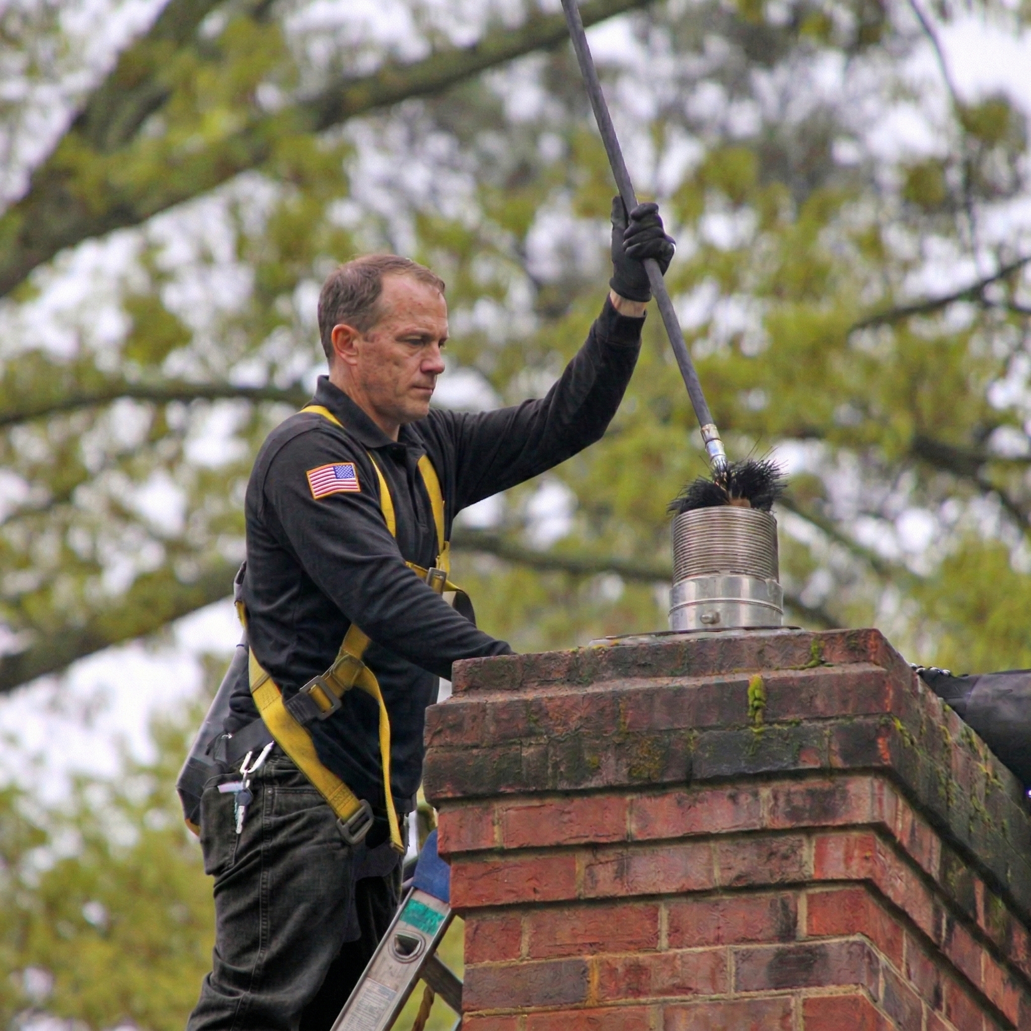 Chimcare technician sweeping a chimney on a roof Chimcare technician sweeping a chimney on a roof